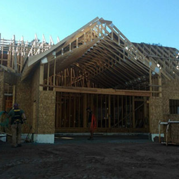 Construction site of a building with exposed wooden framework and workers present.