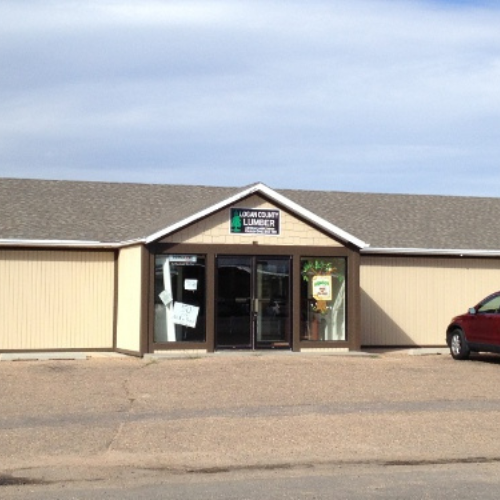 A beige building with a peaked roof features a central glass door under a sign reading 