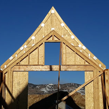 Construction framework of a house under a clear blue sky.
