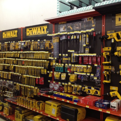Store aisle displaying a variety of DeWalt tools and accessories. Products are neatly organized with yellow and black packaging on shelves.