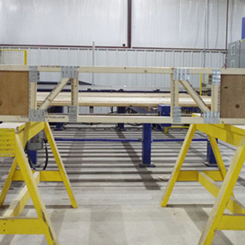 A wooden workbench made of two saw horses and wooden planks, set up in a warehouse or workshop environment.