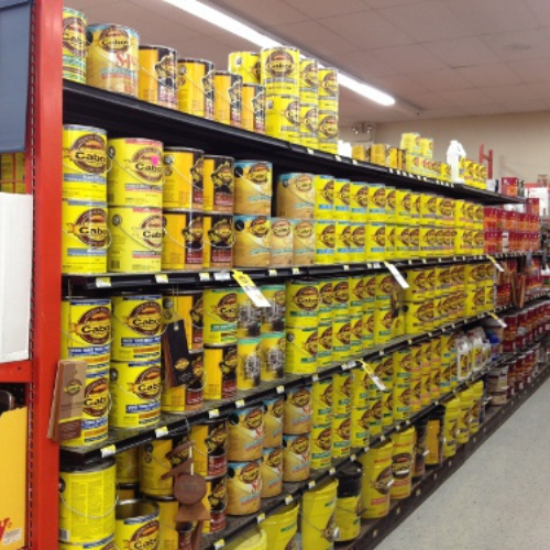 Shelves stocked with bright yellow cans of wood stain in a hardware store, creating an orderly and vibrant display of DIY supplies.