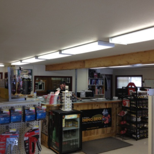 A hardware store interior with shelves of tools and supplies. A counter displays a 