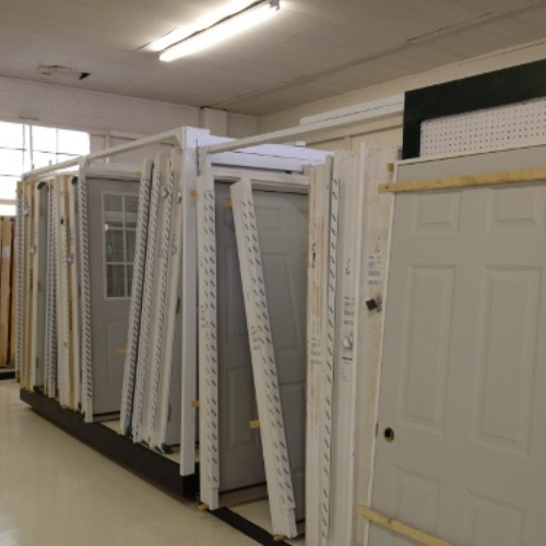 A hardware store display features several white and gray doors in frames, neatly arranged in a well-lit room, conveying a sense of order and selection.