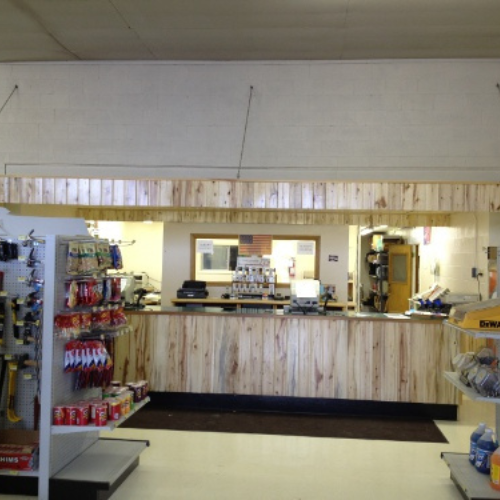 A hardware store counter with light wood paneling, surrounded by shelves displaying various tools and supplies, creating a welcoming atmosphere.