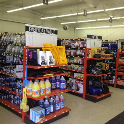 A hardware store aisle with bright lighting shows neatly organized shelves labeled 