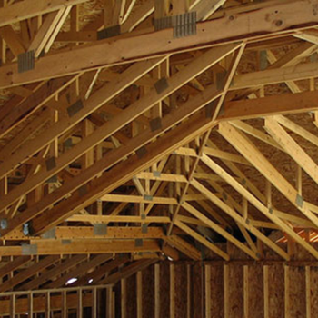 Wooden rafters and trusses in a building under construction, showcasing the framework of the roof.