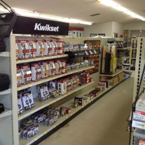 Hardware store aisle with shelves displaying various locks and door hardware under a 