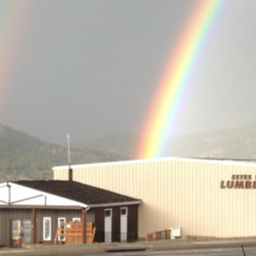 A vibrant rainbow arcs into a beige industrial building labeled 